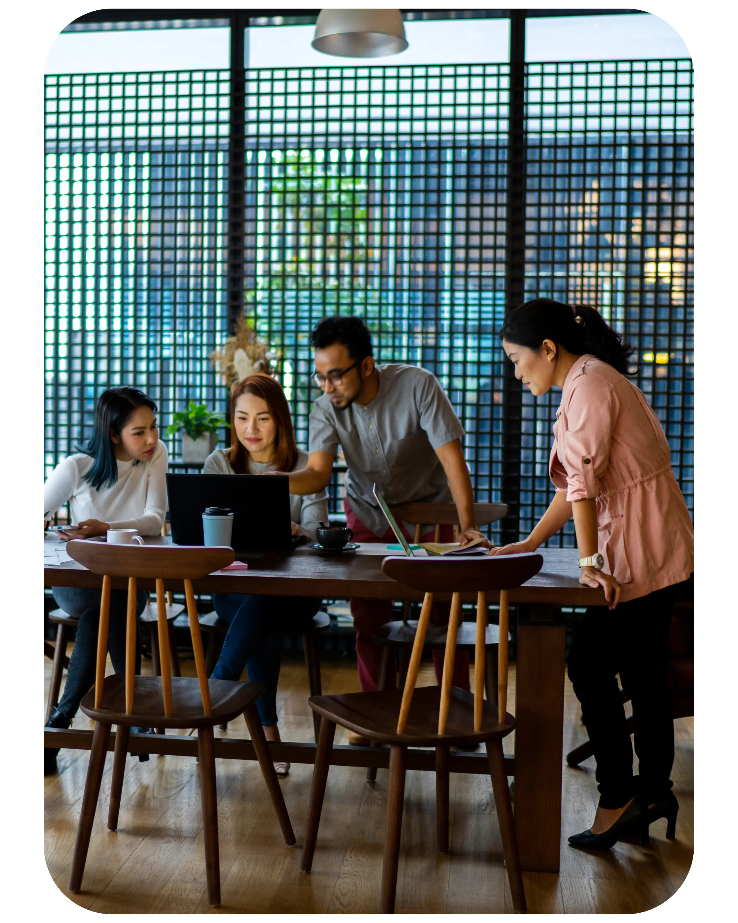 A team collaborating around a laptop in a modern workspace